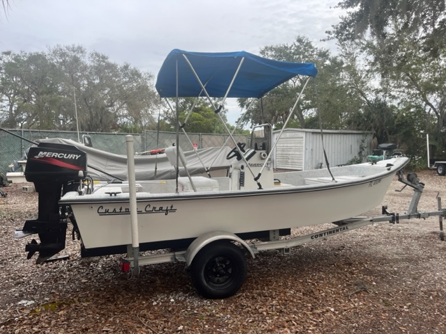 A white 19 foot Custom Craft with a Mercury Outboard motor.